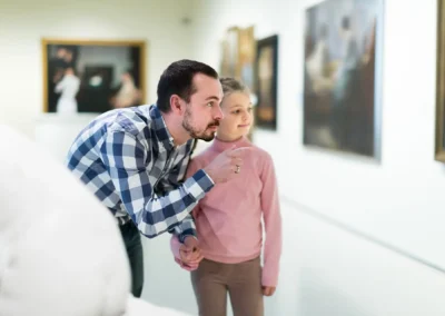 Mann befindet sich mit kleinem Mädchen in Museum und zeigt auf eines der Bilder, die an der Wand hängen